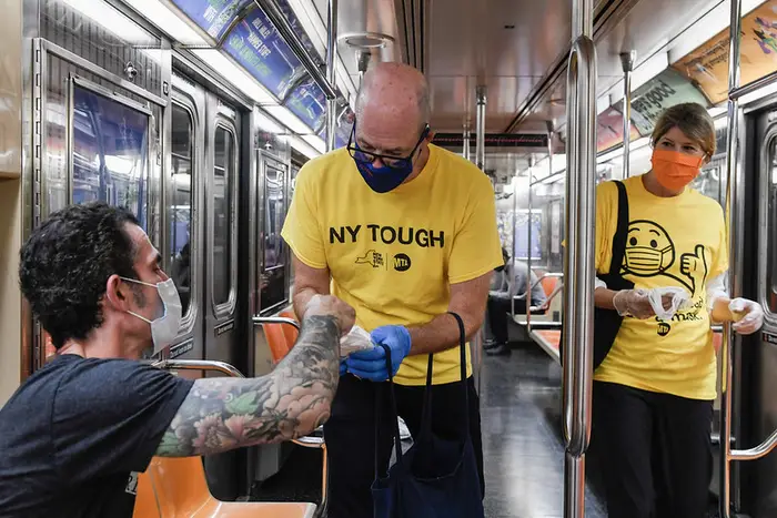 MTA Mask Force volunteers wearing yellow shirts hand out surgical masks to subway riders on the 1 line in Manhattan in September, 2020.